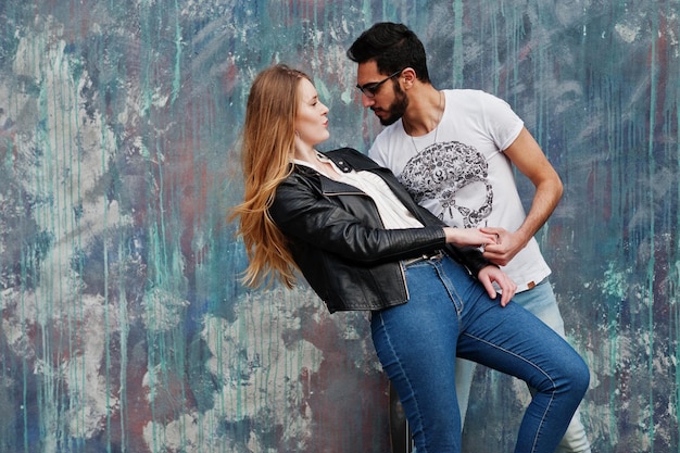 Genial pareja multirracial posando contra la pared y bailando