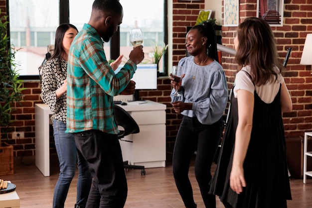 Gente alegre bailando en un evento de celebración de amistad celebrado en casa mientras disfruta de bebidas alcohólicas. Felices amigos cercanos escuchando música de fiesta mientras beben vino y celebran cumpleaños.