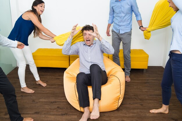 Gente alegre golpeando a su amigo con almohadas