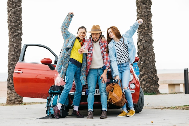 Foto gratuita gente alegre tomando selfie cerca de auto rojo