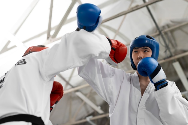 Foto gratuita gente de ángulo bajo practicando taekwondo.