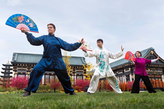 Gente de ángulo bajo practicando tai chi al aire libre