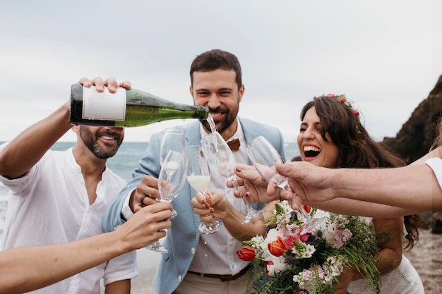 Foto gratuita gente celebrando con sus amigos casándose en la playa