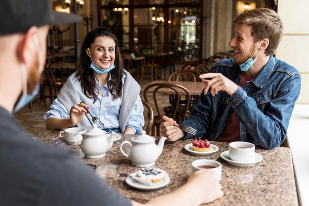 Gente charlando en el restaurante con máscaras faciales.