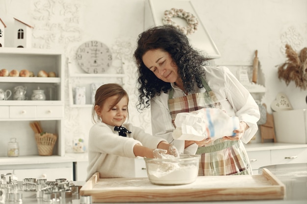 Gente en una cocina. Abuela con hija pequeña. Mujer adulta enseñar a la niña a cocinar.