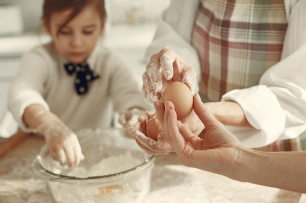 Gente en una cocina. Abuela con hija pequeña. Mujer adulta enseñar a la niña a cocinar.