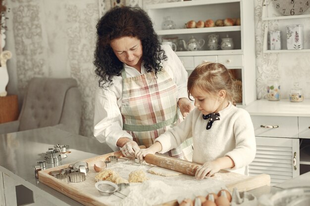 Gente en una cocina. Abuela con hija pequeña. Mujer adulta enseñar a la niña a cocinar.