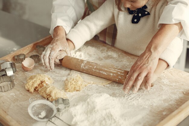 Gente en una cocina. Abuela con hija pequeña. Mujer adulta enseñar a la niña a cocinar.