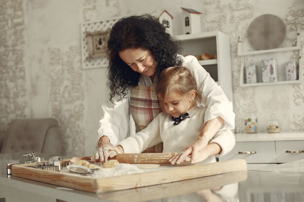 Gente en una cocina. Abuela con hija pequeña. Mujer adulta enseñar a la niña a cocinar.