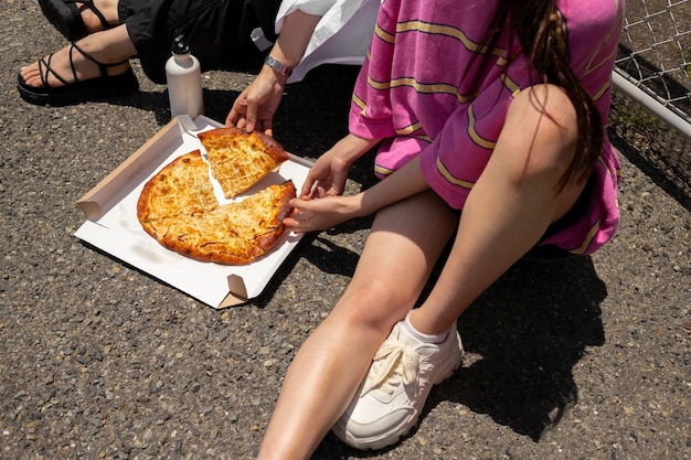 Gente disfrutando de un bocadillo de pizza al aire libre