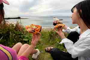 Foto gratuita gente disfrutando de pizza juntos al aire libre