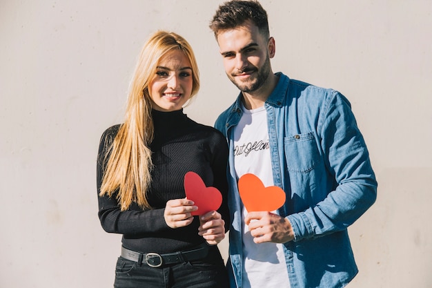 Gente encantadora con corazones mirando a cámara