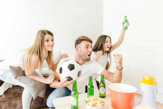 Gente feliz gritando viendo fútbol en casa