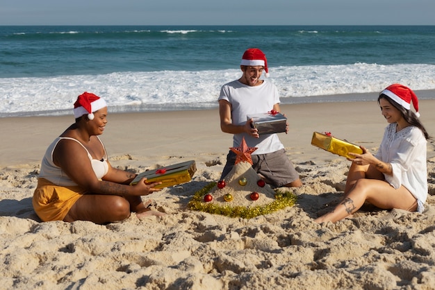 Foto gratuita gente feliz de tiro completo con regalos en la playa