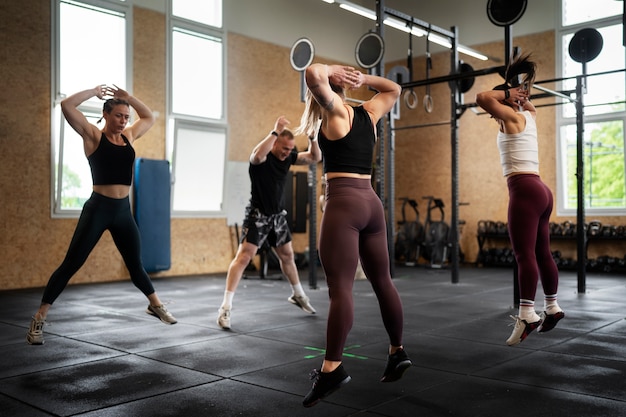 Gente en forma de tiro completo haciendo burpees en el gimnasio