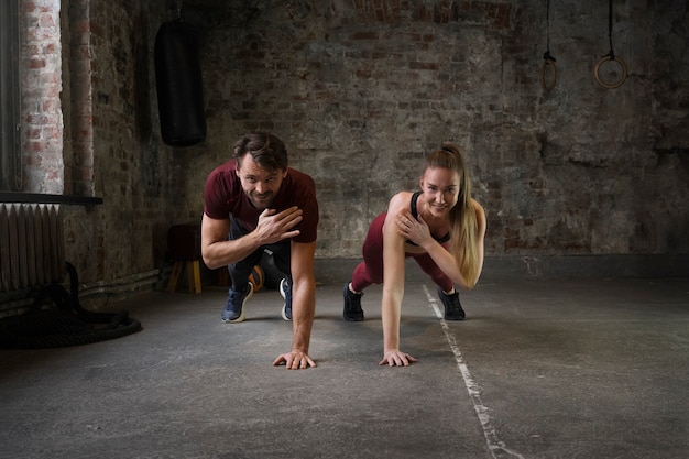 Gente en forma de tiro completo haciendo burpees juntos