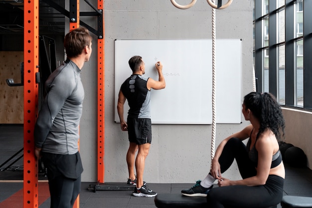 Gente en el gimnasio hablando y haciendo planes de ejercicio.