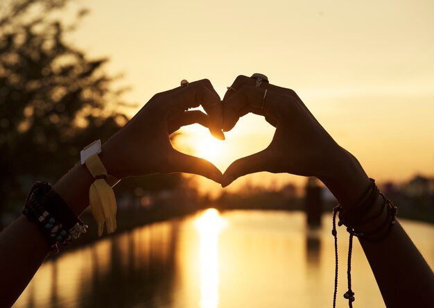 Gente haciendo manos en forma de corazón silueta Puesta de sol