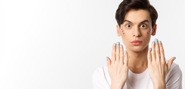 Gente lgbtq y concepto de belleza hermoso hombre gay mostrando esmalte de uñas azul en las uñas y mirando