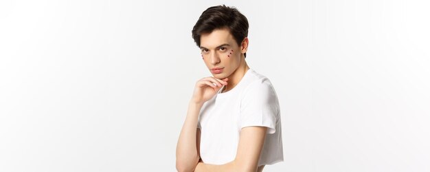 Gente lgbtq y concepto de belleza hermoso modelo masculino andrógino con brillo en la cara usando crop t