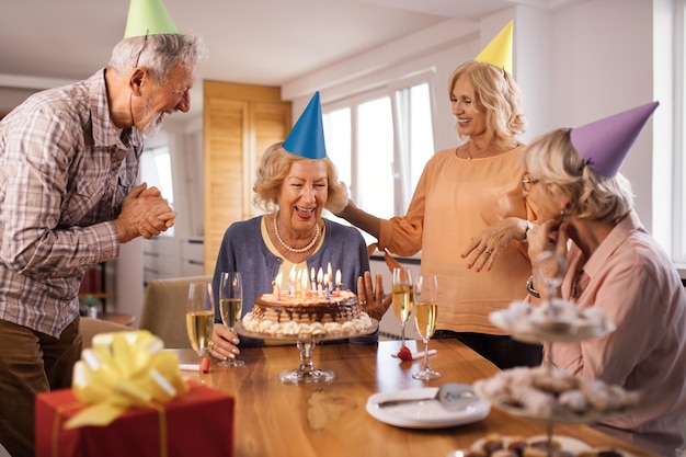 Gente madura feliz celebrando el cumpleaños de sus amigos y divirtiéndose en casa