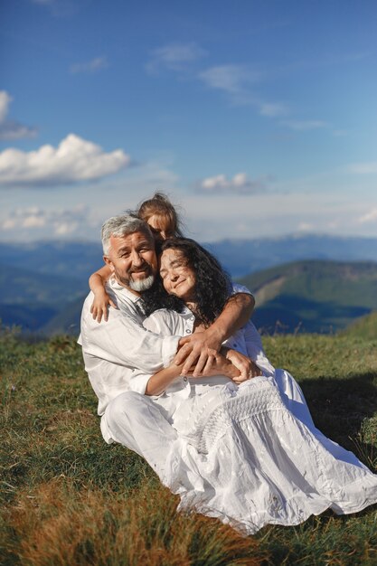 Gente en una montaña. Abuelos con nietos. Mujer con un vestido blanco.