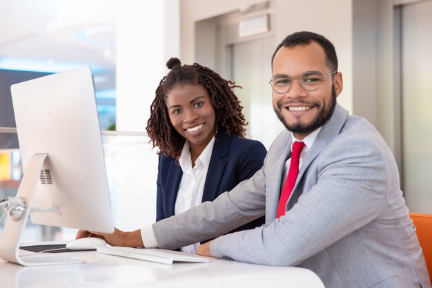 Gente de negocios alegre con computadora de escritorio