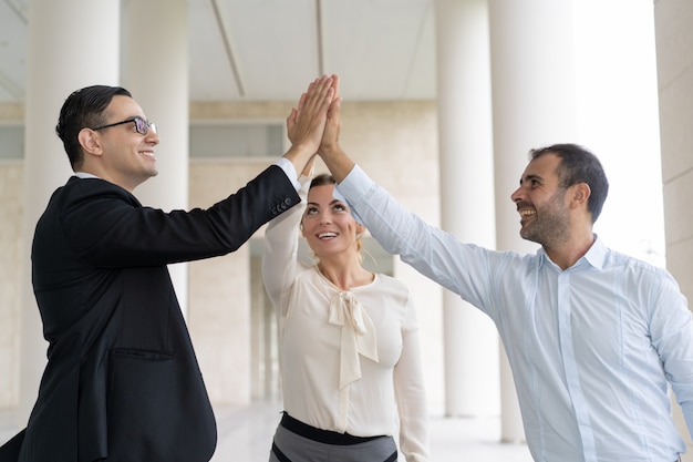 Gente de negocios alegre que da cinco altos para celebrar el éxito