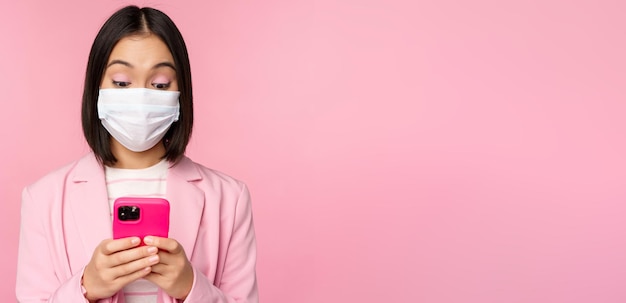 Gente de negocios y concepto covid joven empresaria asiática en traje y mascarilla médica usando smar