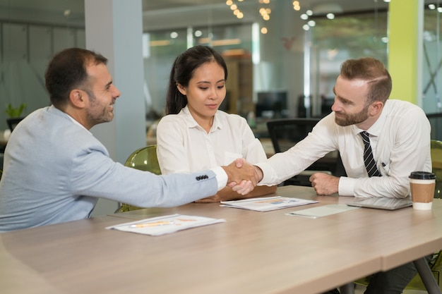 Gente de negocios dándose la mano en el escritorio en la oficina