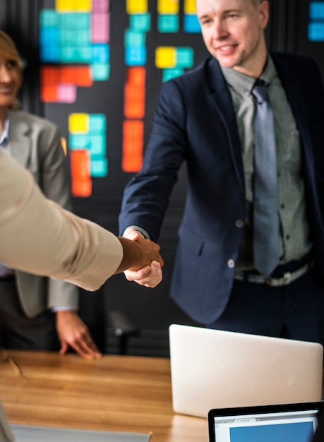 Gente de negocios dándose la mano en una sala de reuniones