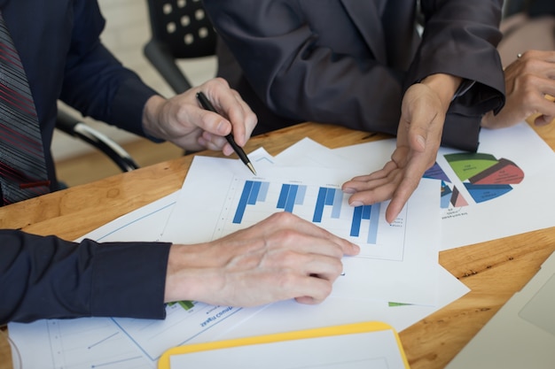 Gente de negocios discutiendo las tablas y gráficos que muestran los resultados de su exitoso trabajo en equipo.