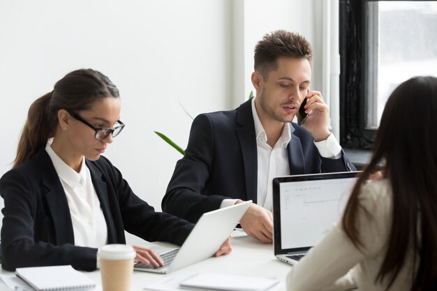 Gente de negocios ejecutiva usando computadoras portátiles para el trabajo, hablando por teléfono