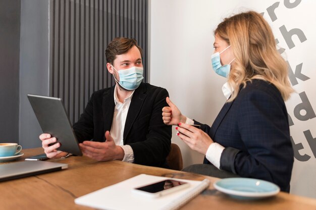 Gente de negocios hablando de un nuevo proyecto mientras usan máscaras médicas