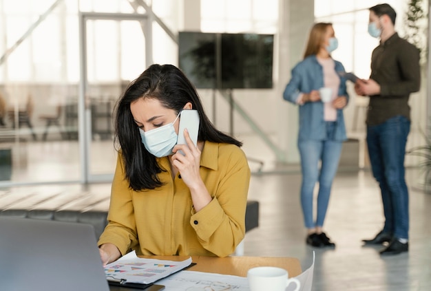 Foto gratuita gente de negocios con máscaras médicas en el trabajo