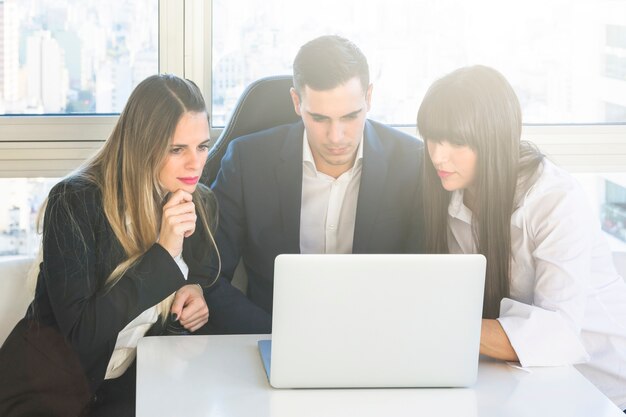 Gente de negocios mirando portátil en la reunión