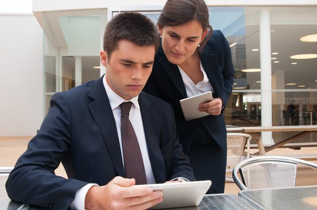 Gente de negocios navegando en tabletas y leyendo noticias en la mesa