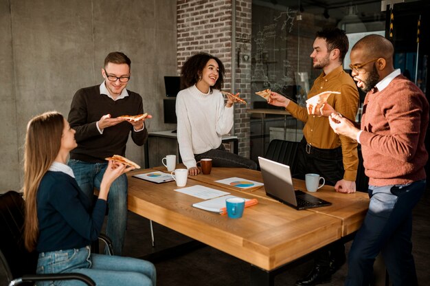 La gente de negocios con pizza durante un descanso de la reunión de oficina