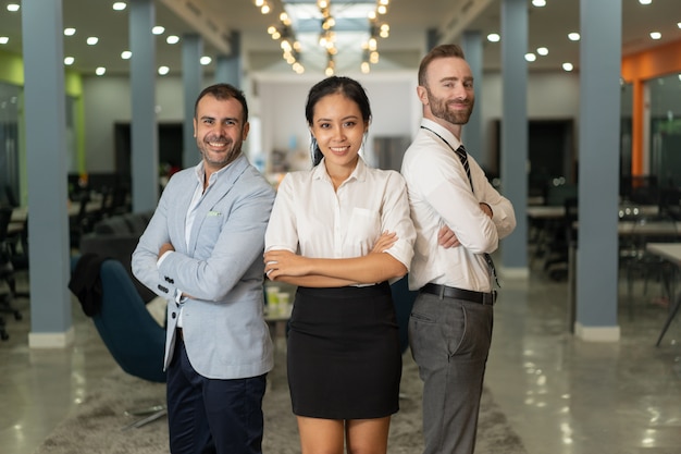 Gente de negocios sonriente mirando la cámara y posando en la oficina