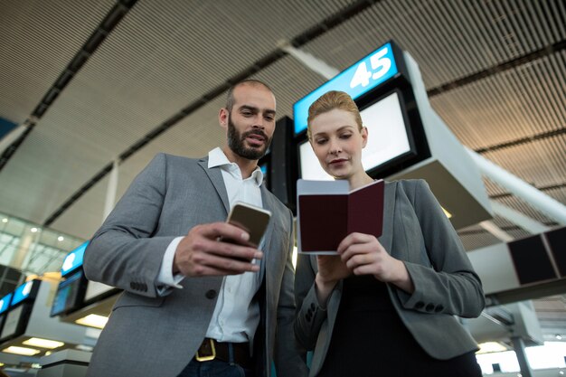 Gente de negocios con tarjeta de embarque y uso de teléfono móvil
