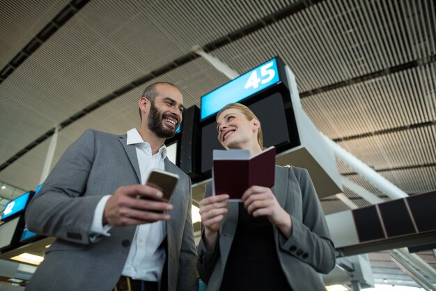 Gente de negocios con tarjeta de embarque y uso de teléfono móvil