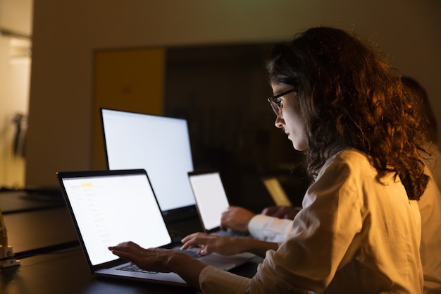 Gente de negocios usando computadoras en la oscura oficina