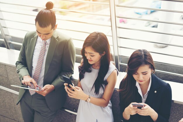 Gente de negocios utilizando el teléfono inteligente mientras están juntos