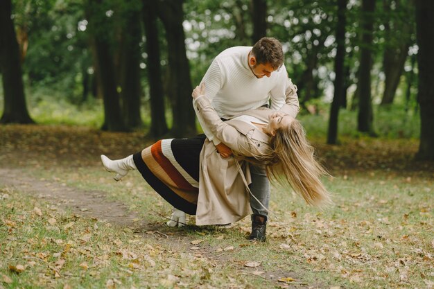 Gente en un parque. Mujer con un abrigo marrón. Hombre con un suéter blanco.