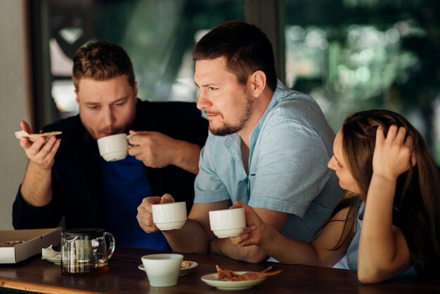 Gente pensativa tomando café y comiendo pizza en la cafetería