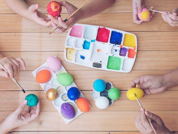 Gente pintando coloridos huevos de Pascua - concepto de celebración de vacaciones de semana Santa