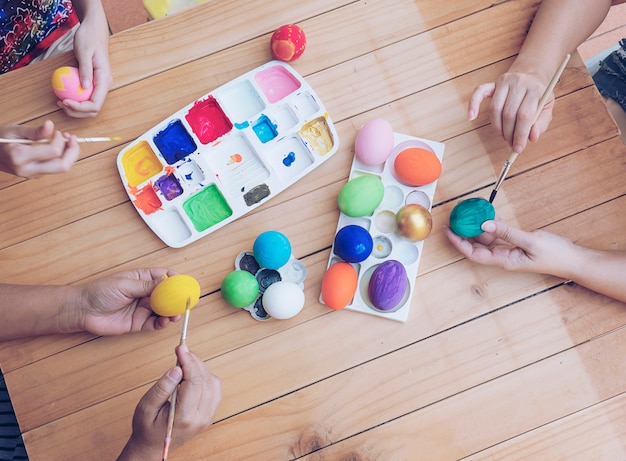 Gente pintando coloridos huevos de Pascua - concepto de celebración de vacaciones de semana Santa