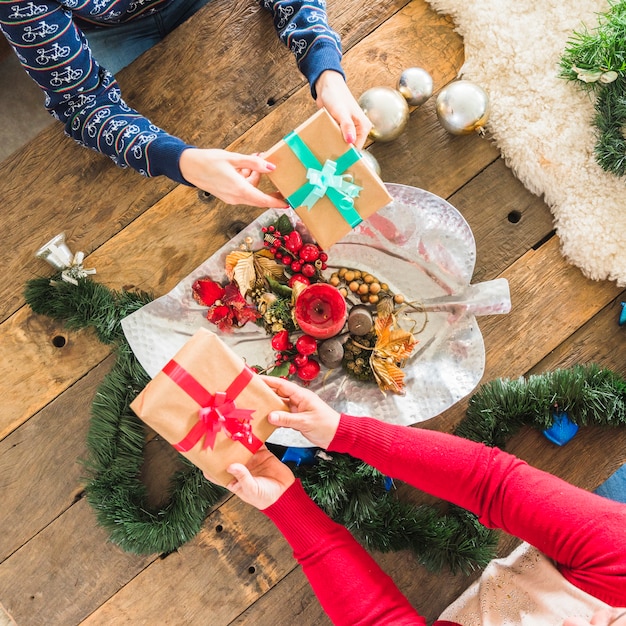 Foto gratuita gente presentando regalos en mesa decorada para navidad.