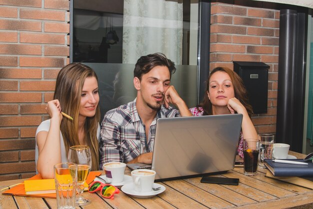 La gente que estudia con la computadora portátil en el café