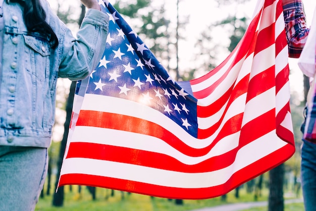 Gente que sostiene la bandera de Estados Unidos en el parque